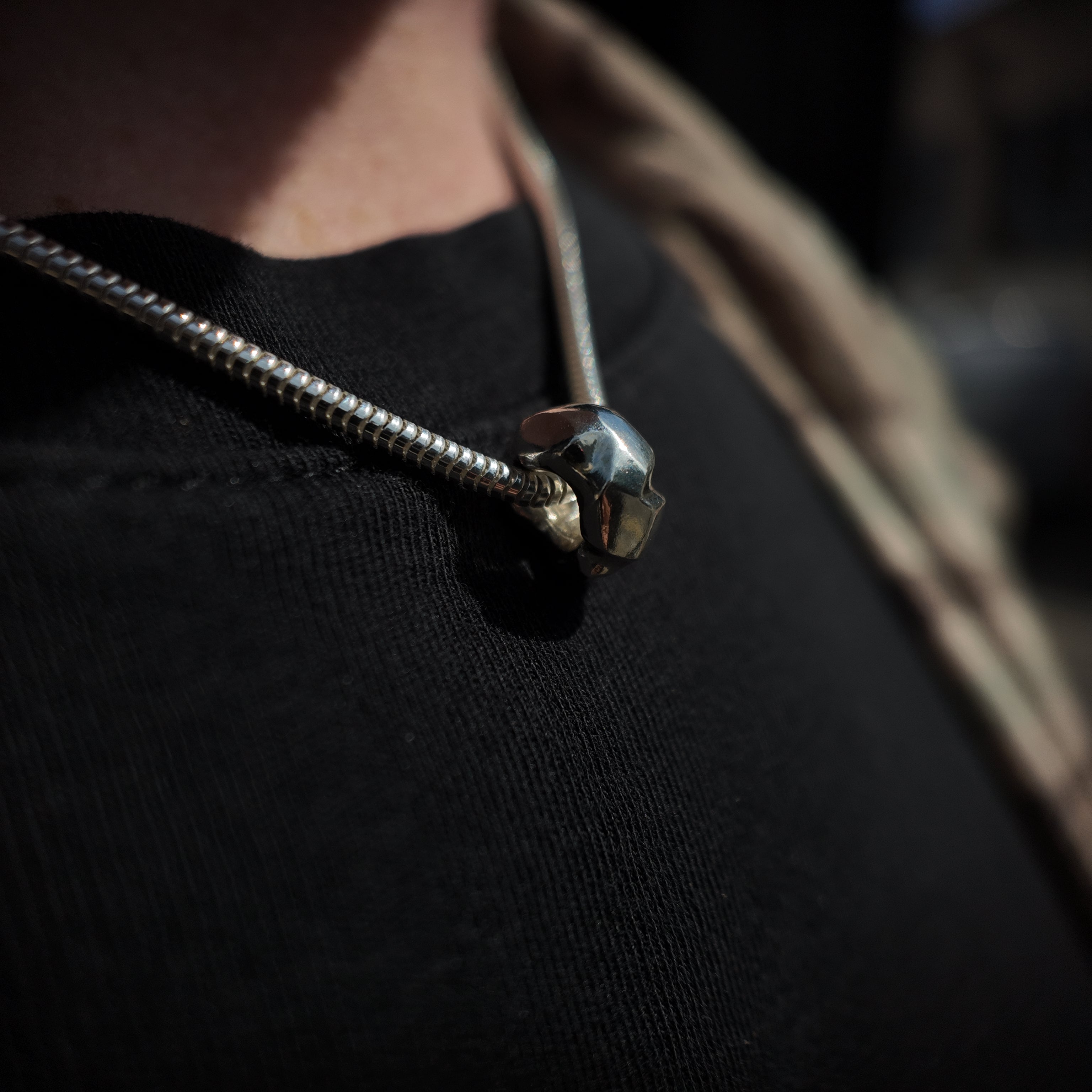 Carved silver donut necklace macro shot around neck