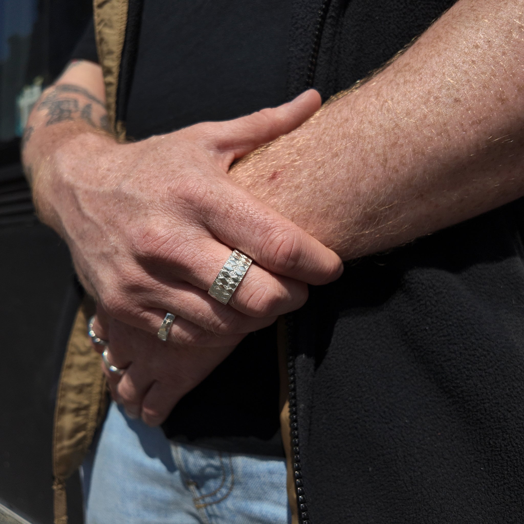 Chequered silver square ring with polished finish on hand with hand holding wrist