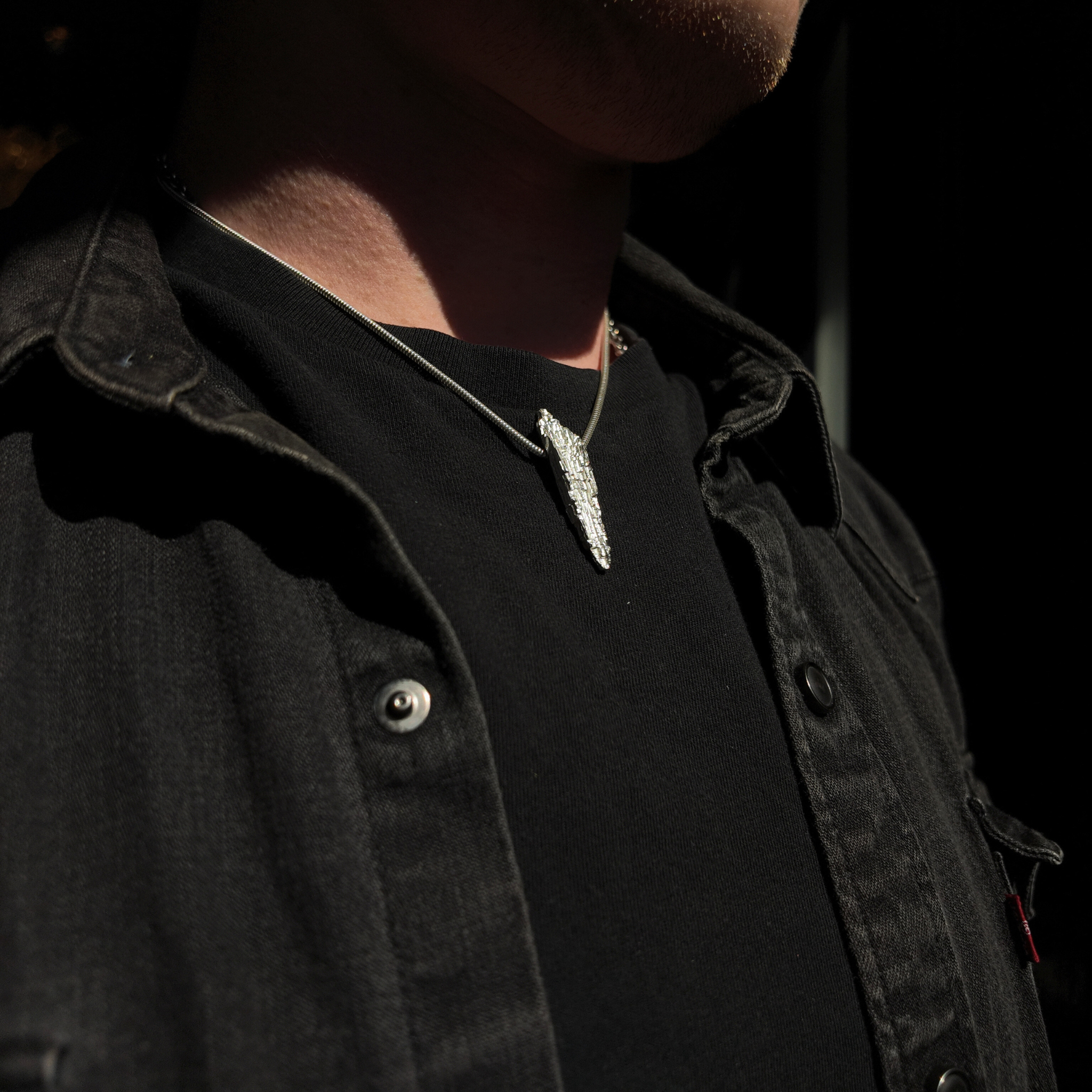 Luna silver necklace on a snake chain around a mans neck