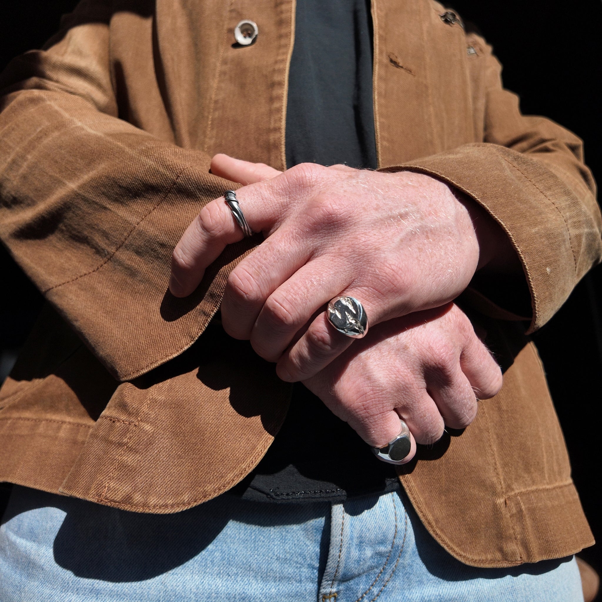 Slashed small silver signet ring with a polished finish on a mans hand