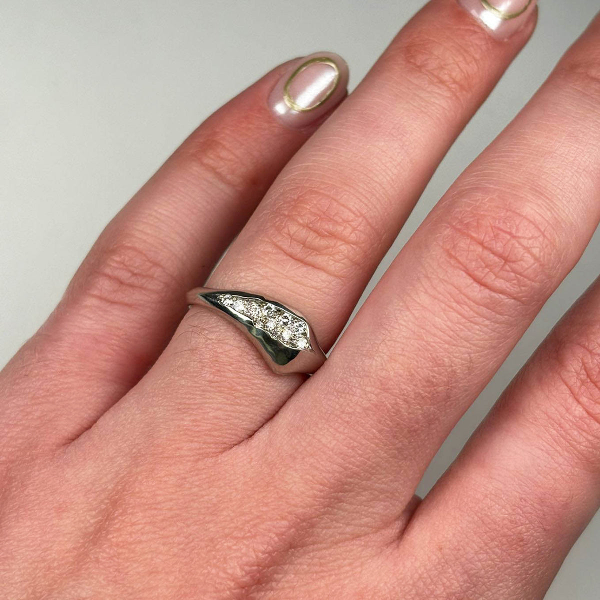 Handmade in platinum, the ring tapers from 7.5mm to 2.75mm in width and is pavé set with 12 white diamonds.
