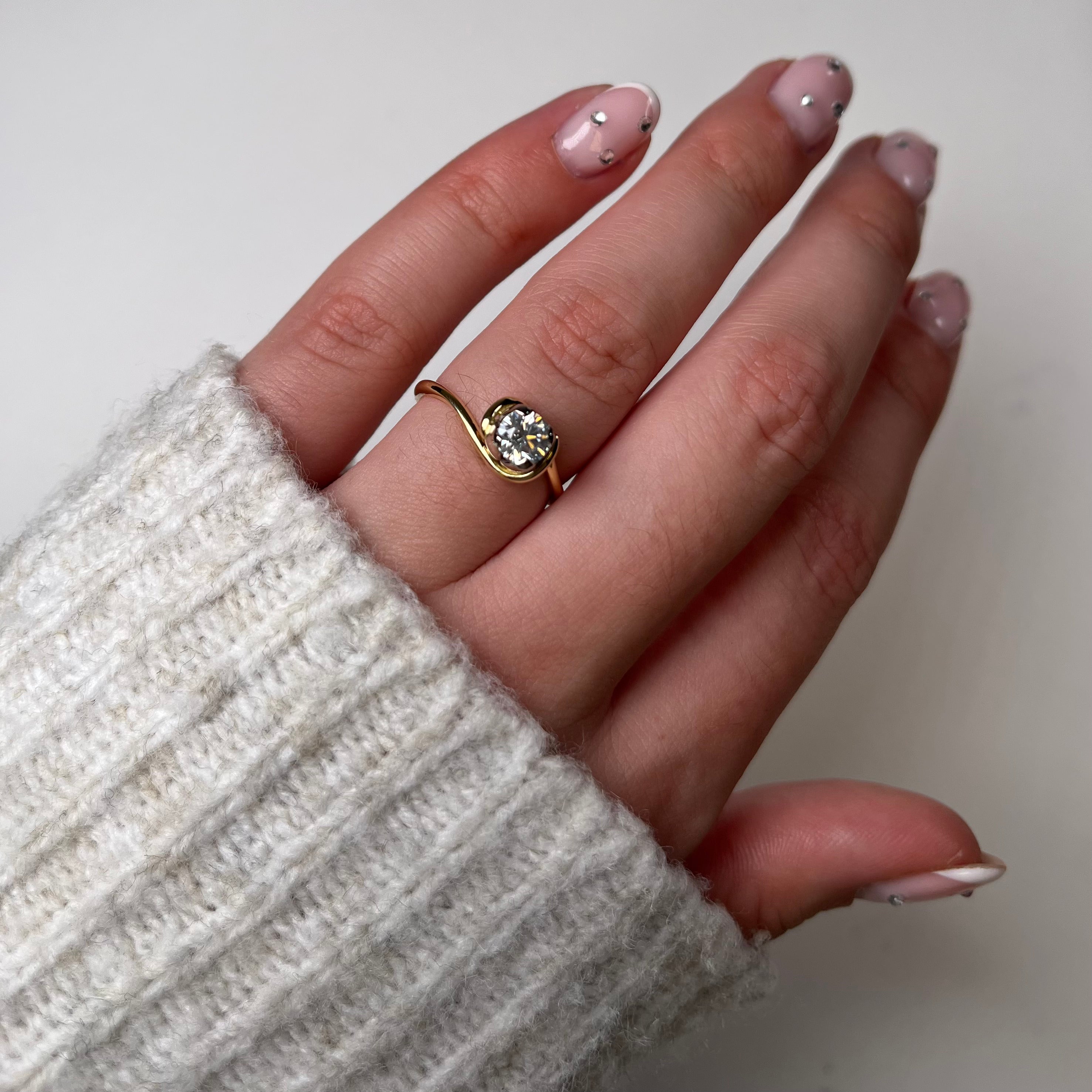 An 18ct yellow gold simple fine band with contrasting four-petal setting in platinum. Set with .20pt or .50pt round, brilliant cut diamond.