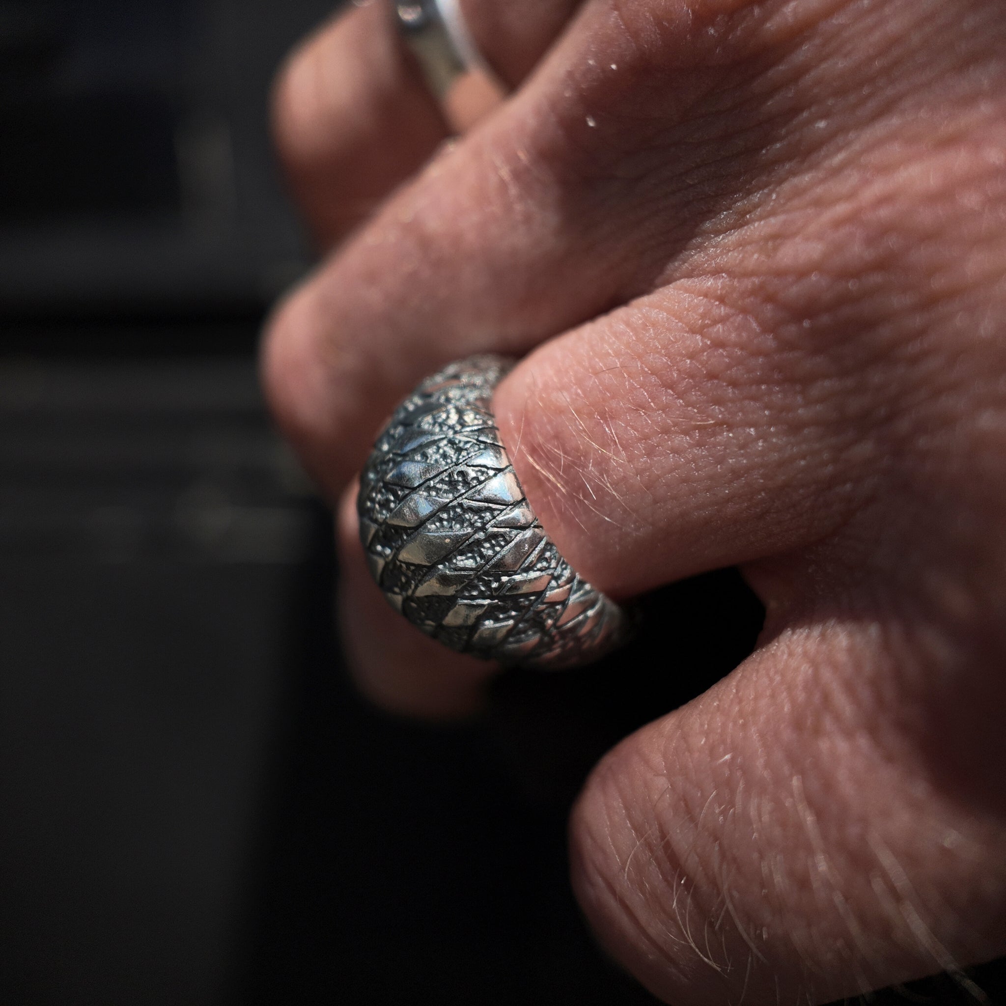 chequered bombe ring in oxidised finish on hand with a macro lens