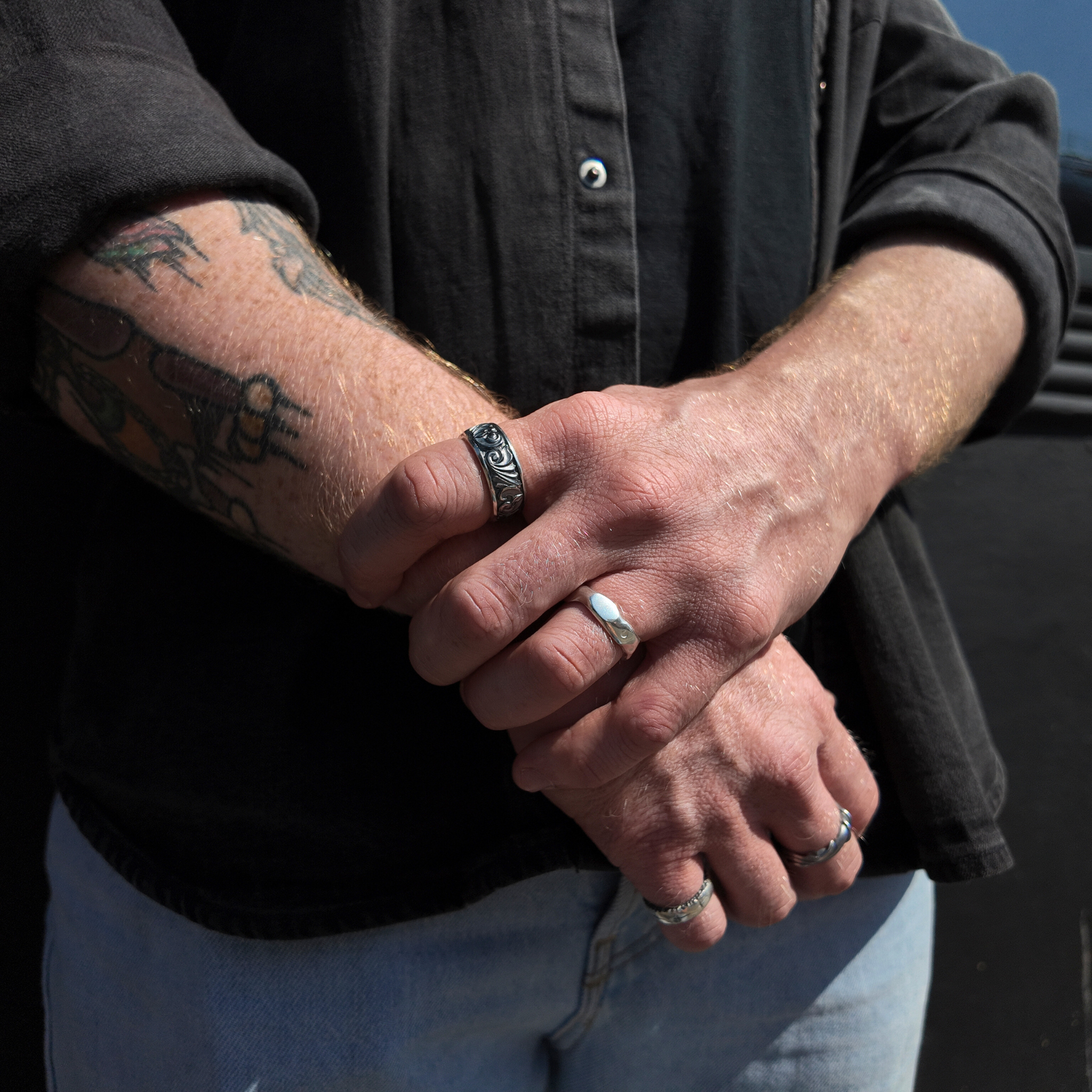 silver gun engraved ring on hand with hand holding wrist