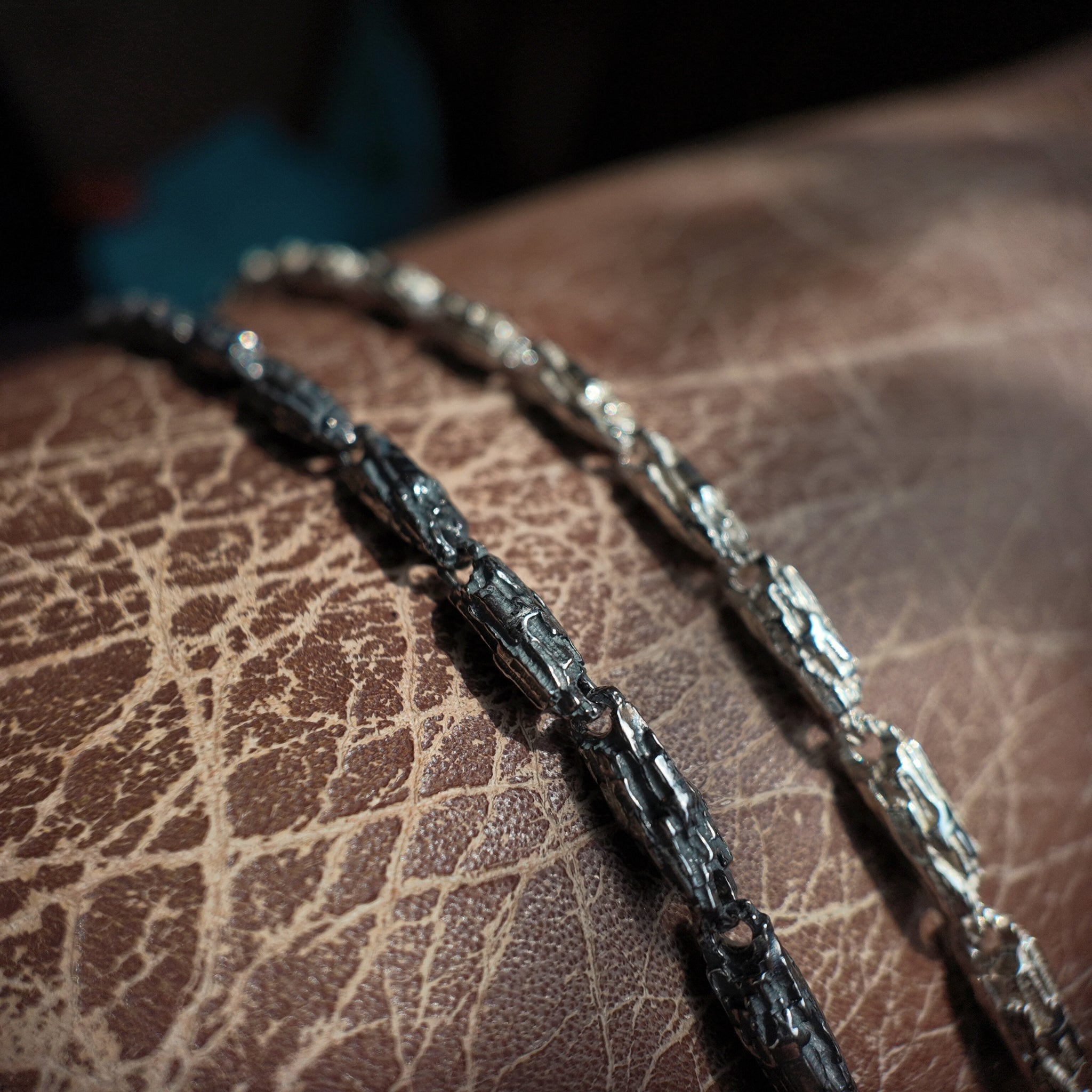 2 small luna silver bracelets on a chair arm. One is oxidised the other is polished.