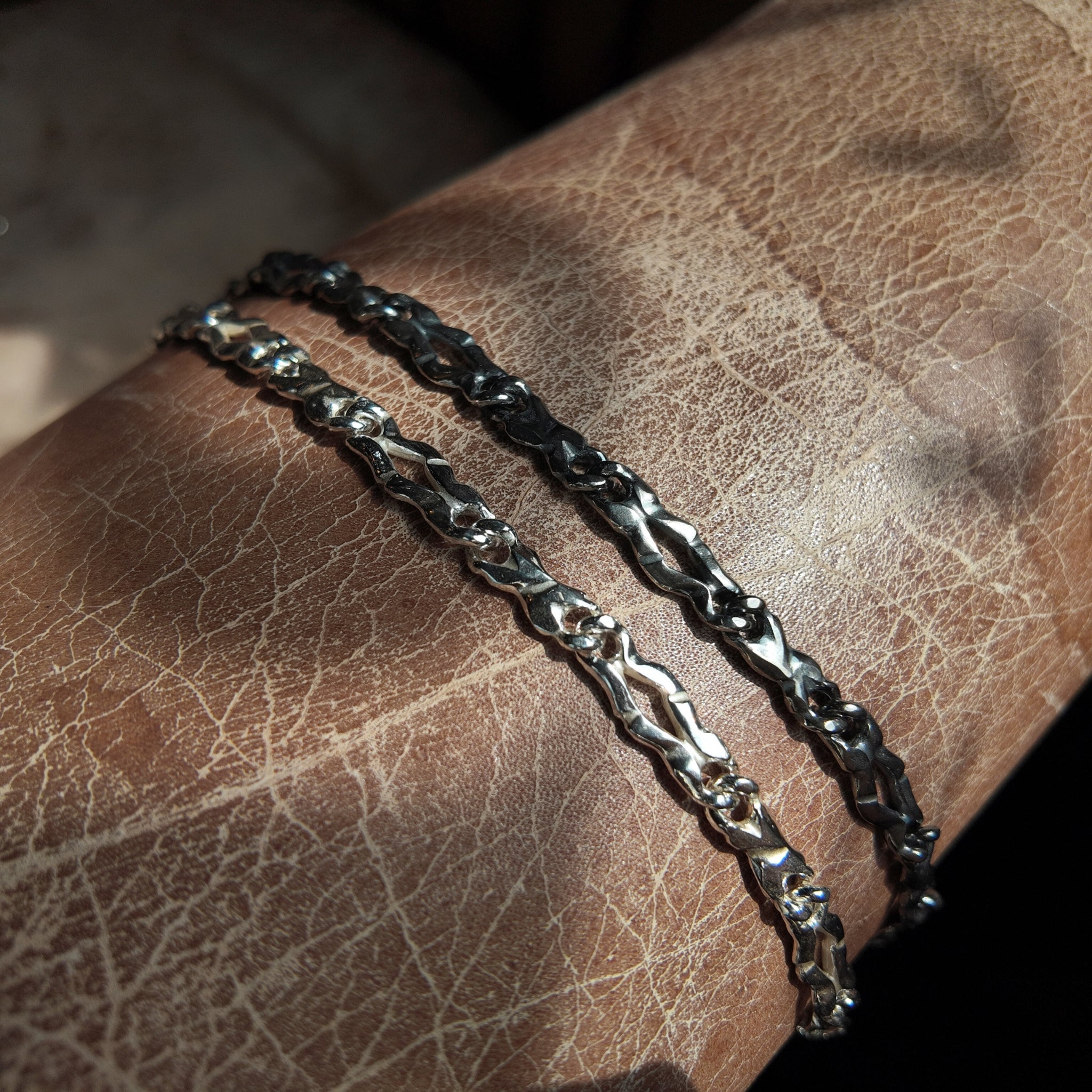 an oxidised and a polished version of the carved link silver bracelet
