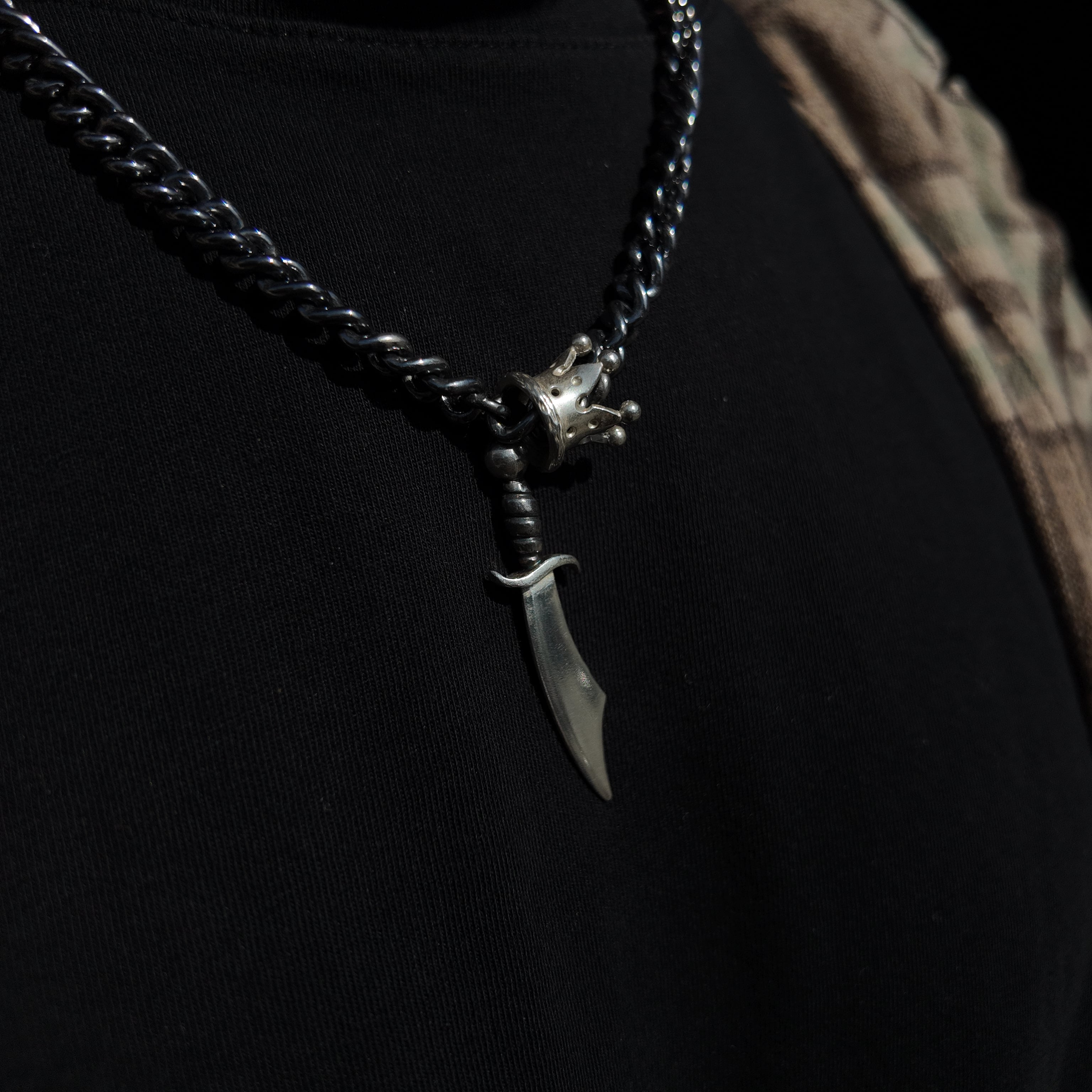 King & Queen silver necklace with sabre and crown around neck macro shot