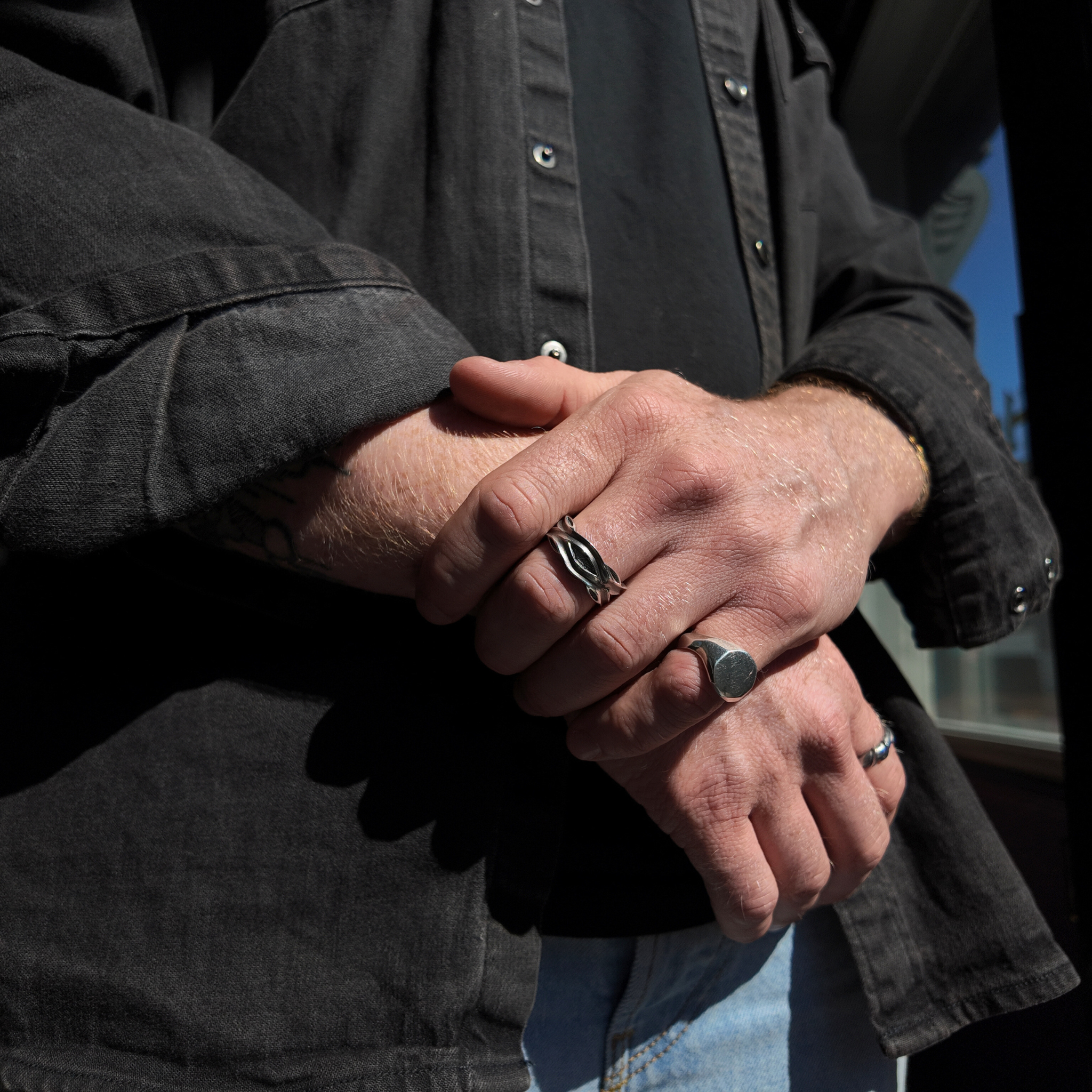 Libertine silver 8mm ring with an oxidised finish on a mans hand whilst he is holding his other wrist