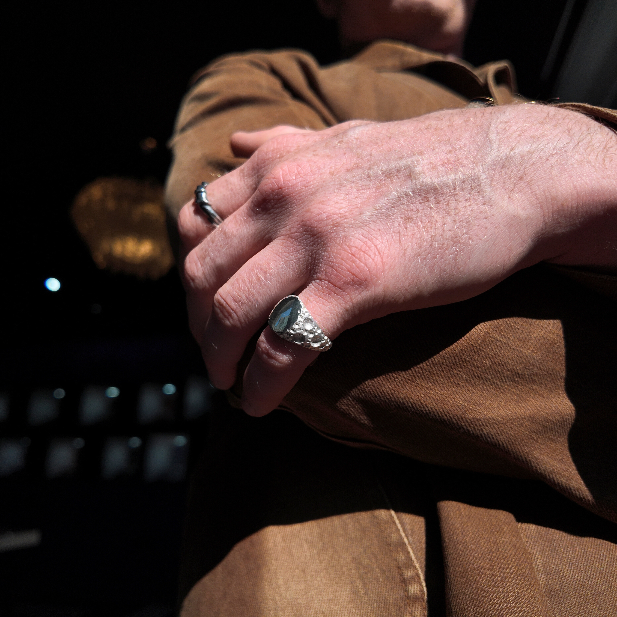 Moon small silver signet ring on a mans pinky finger