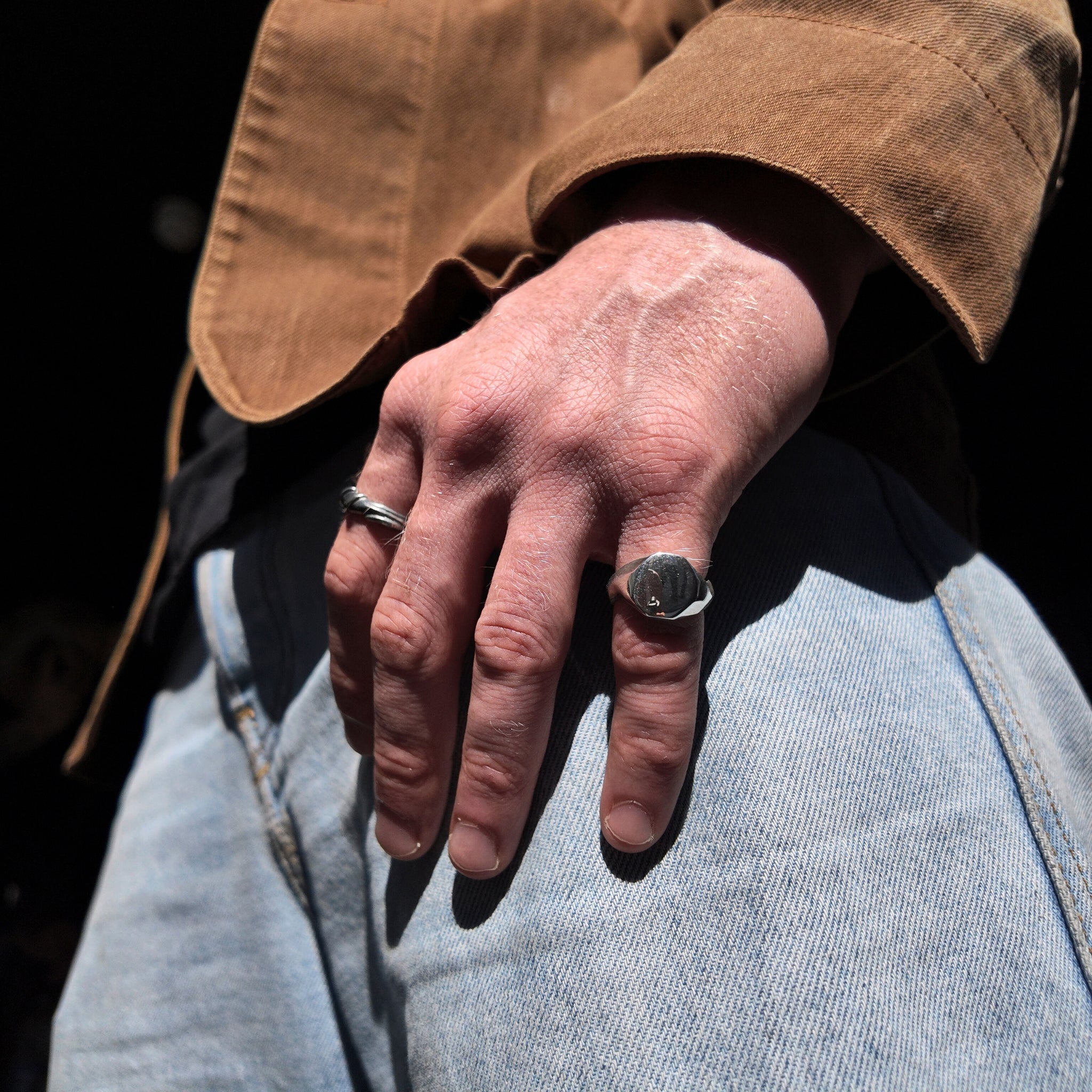 Small Carved silver signet ring on a mans pinky finger